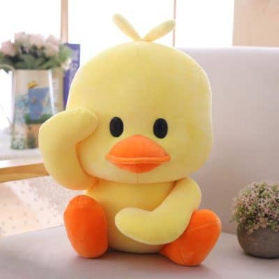 Plush yellow duck toy with orange feet and beak, cute cartoon design, perfect for children, comfort toy, soft plush material, adorable decorative item for kids' rooms.