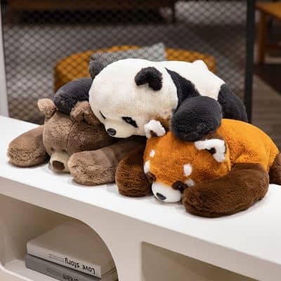 Soft plush panda, dog, and bear stuffed toys displayed on a white table at Monalisa Store for cozy comfort and playful decor.