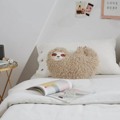 Fluffy sloth-shaped decorative pillow on a cozy bed, perfect for bedroom decor and comfort, from Monalisa Medical's stylish product collection.