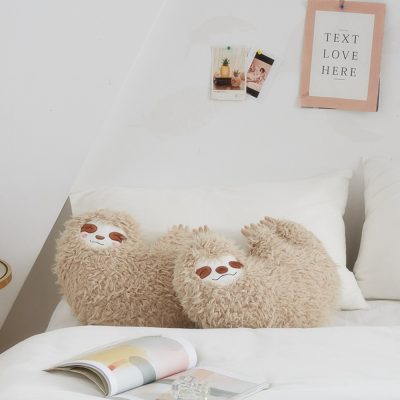 Fluffy sloth plush pillows on a cozy white bed with decorative wall art, perfect for cozy living spaces and bedroom decor.