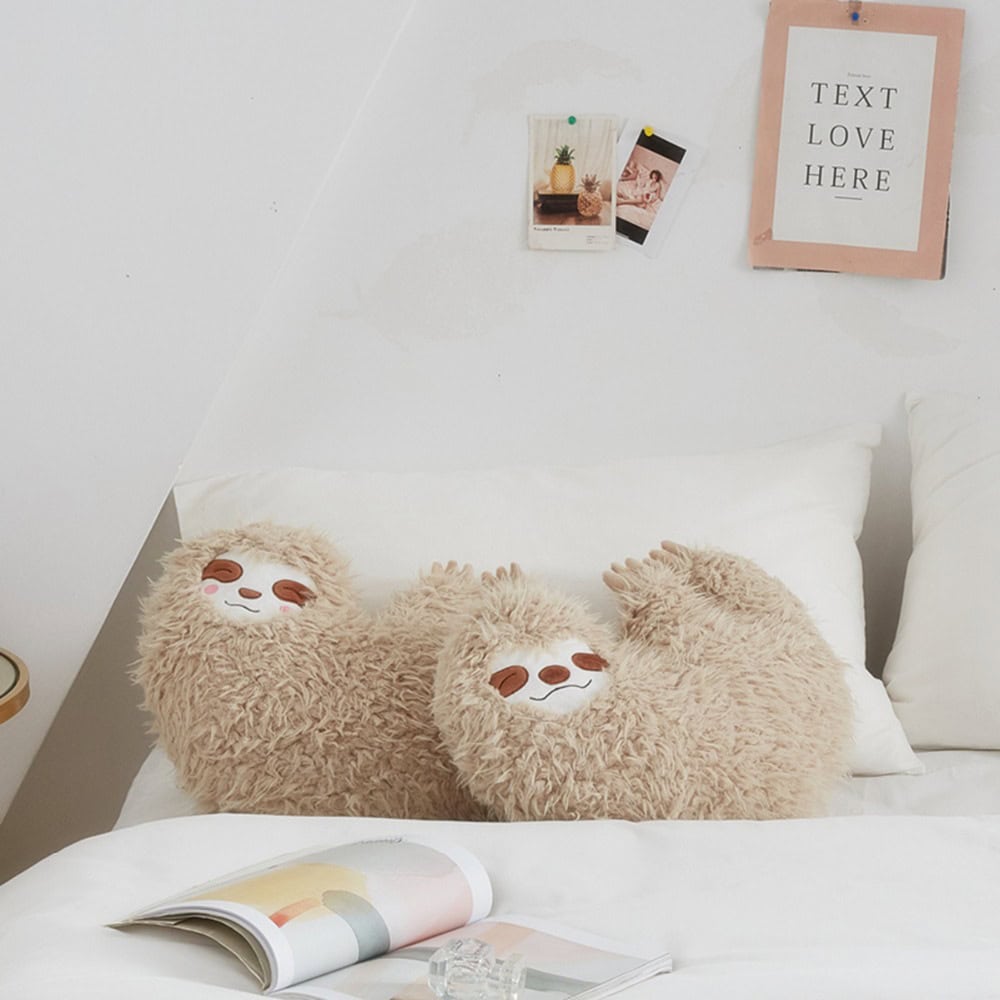 Fluffy sloth plush pillows on a cozy white bed with decorative wall art, perfect for cozy living spaces and bedroom decor.