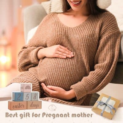 Comfy pregnant woman in cozy sweater holding her belly at home.