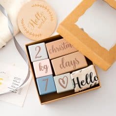 Wooden milestone blocks with "Hello World" and Christmas decorations for baby announcements or gift tags.