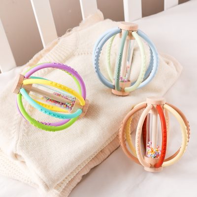Colorful wooden and silicone ball toys with beads for sensory play and development, ideal for babies and toddlers, displayed on soft fabric in a nursery setting.