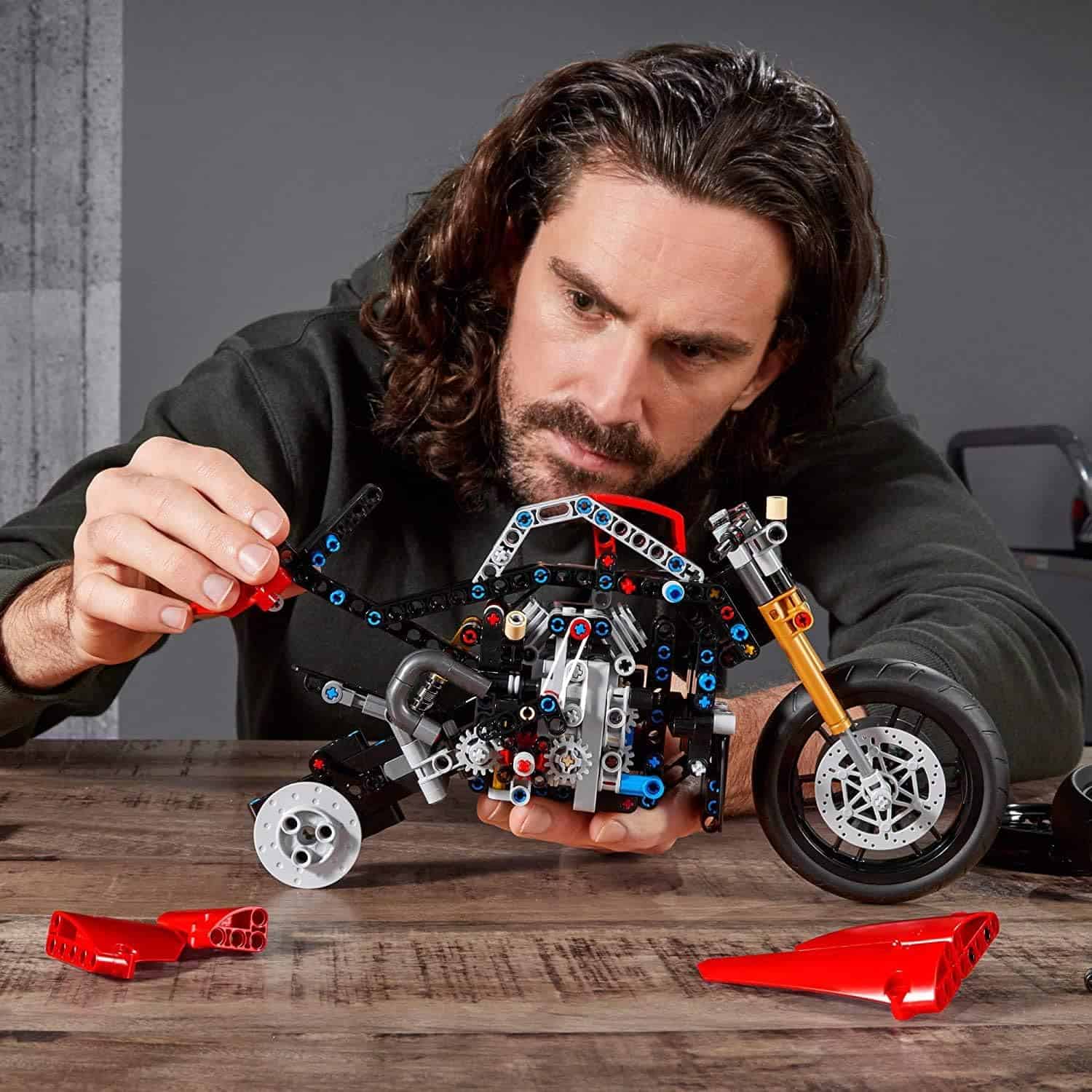 Detailed image of a man assembling a LEGO motorcycle model, focusing on precision and craftsmanship, showcasing fun and creative building. Ideal for tech enthusiasts and LEGO fans.