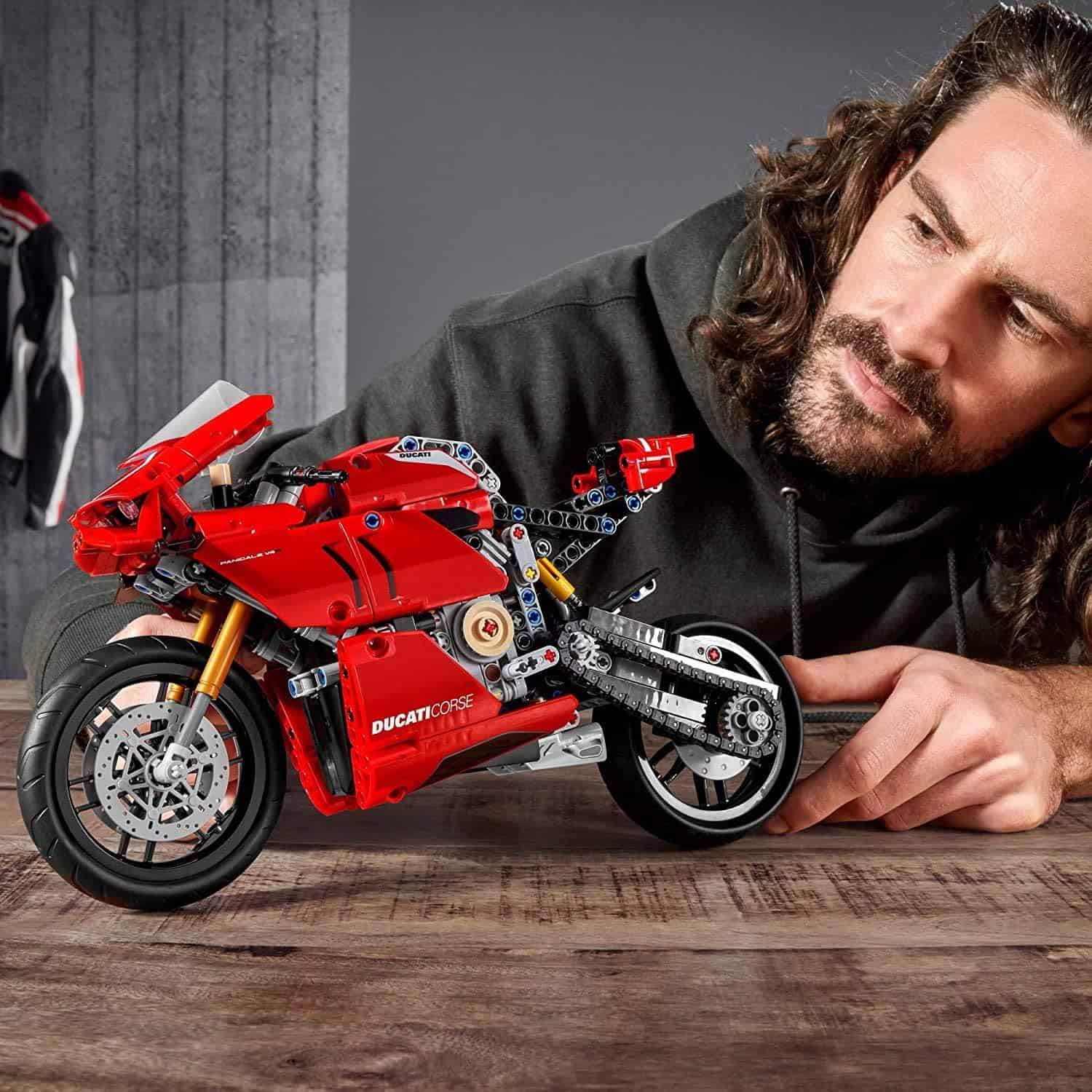 High-quality LEGO Ducati motorcycle model displayed on table with a man examining it, showcasing detailed craftsmanship, perfect for motorcycle enthusiasts and LEGO collectors.