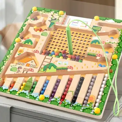 Small wooden marble run game with colorful marbles and green maze-like track for children.