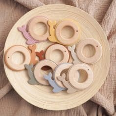 Wooden teether rings for babies with whale-shaped accents in pastel colors, ideal for soothing infants and promoting sensory development, suitable for baby gifts and teething relief.