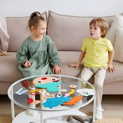 Colorful children's educational toys for imaginative play, featuring face and character pieces on a glass table in a cozy living room setting.