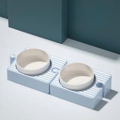 Dog food bowls on a white and blue feeding station for pets, modern pet accessories, Monalisa Store optical shop accessories, sleek pet feeding setup, stylish pet bowls for dogs and cats.