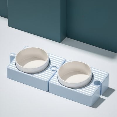 Dog food bowls on a white and blue feeding station for pets, modern pet accessories, Monalisa Store optical shop accessories, sleek pet feeding setup, stylish pet bowls for dogs and cats.