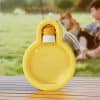Bright yellow floatation device for dogs on a wooden surface with outdoor park background and a child playing with a dog, emphasizing pet safety during water activities.