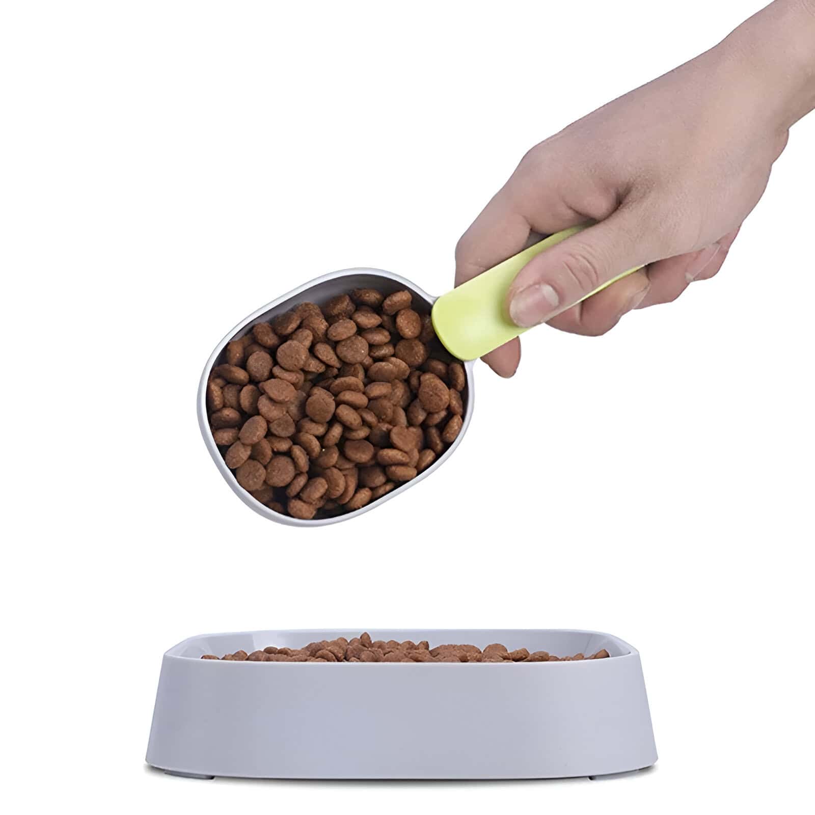 High-quality pet food in a white bowl with a hand scooping dry kibble using a green scoop, ideal for healthy pet nutrition.