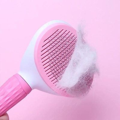 Deep cleaning hairbrush with built-in lint and hair removal feature on a pink background for effective scalp hygiene.