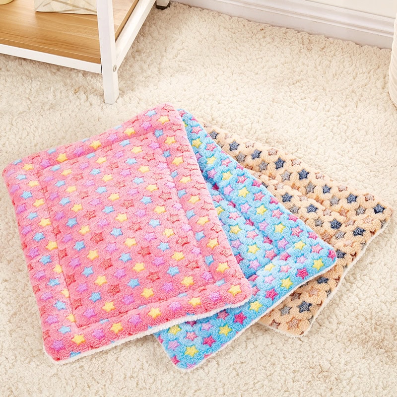 Pink and blue star-patterned microfiber cloths for cleaning or skincare, set of three on a fluffy beige carpet.