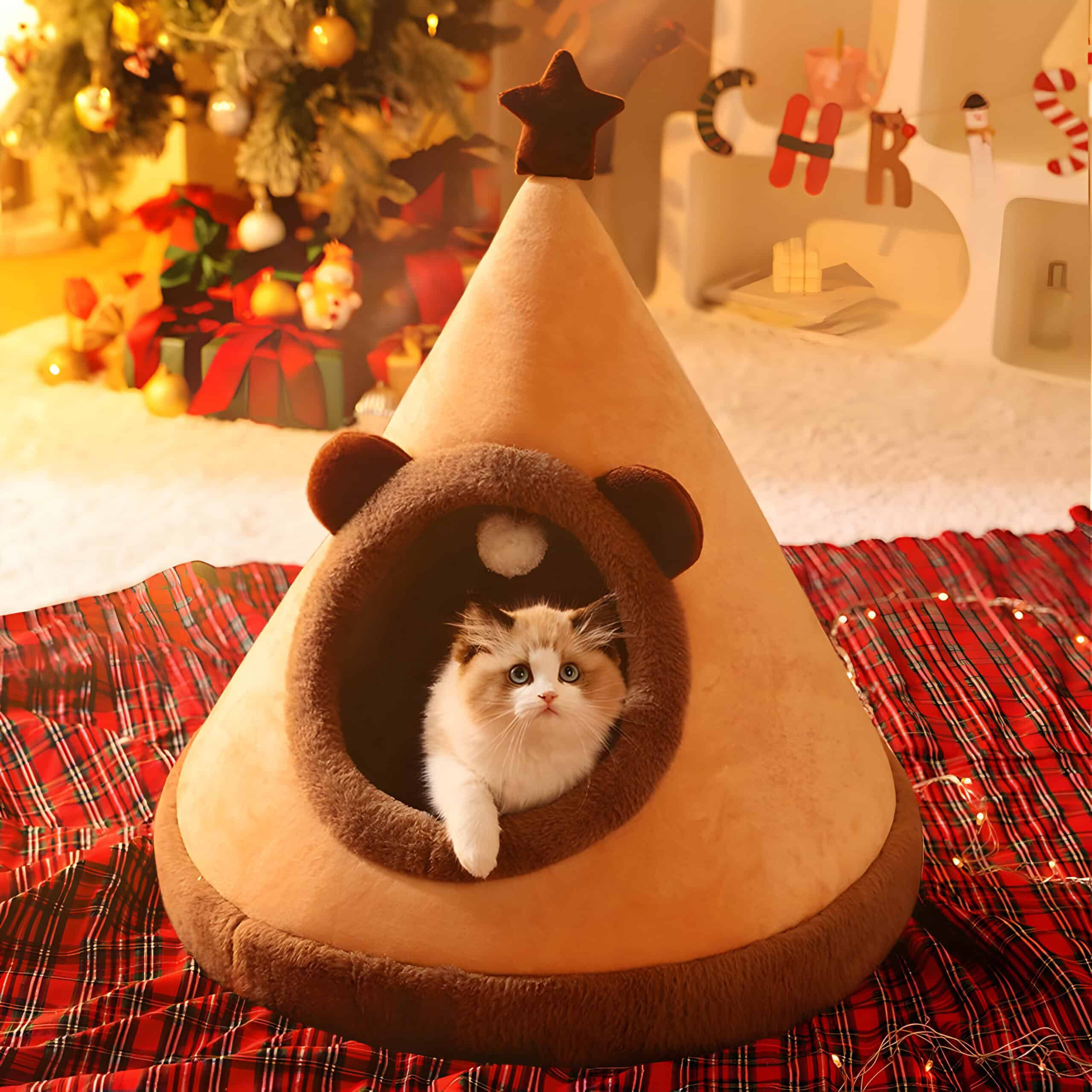 Cozy cat bed shaped like a tepee with a kitten inside, decorated for Christmas with festive background, holiday ornaments, and a decorated tree, perfect for pet comfort and holiday home decor.