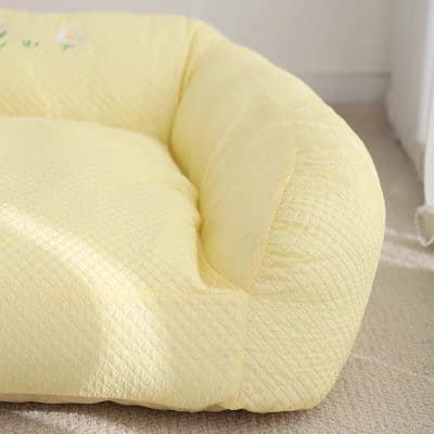 Soft yellow cushioned armchair with quilted fabric, perfect for a relaxing corner in a living room or nursery, featuring a cozy and inviting design.