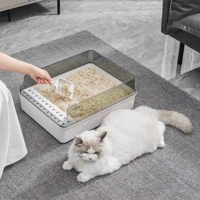 Fresh cat litter box with separate compartments for different types of litter, on a gray carpet with a relaxed Ragdoll cat lying nearby in Monalisa Medical store environment.