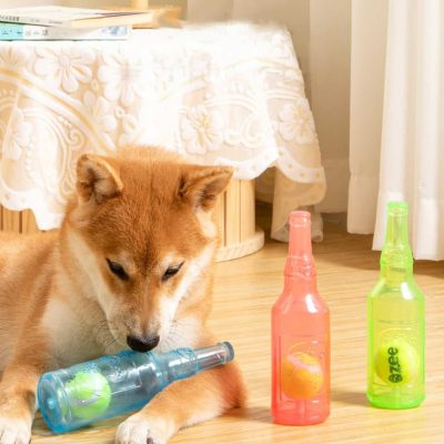 Bright-eyed dog lying on wooden floor near colorful soda bottles, in a cozy indoor setting with natural light, perfect for showcasing pet-friendly, stylish accessories or home decor ideas.