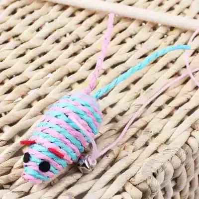 Pink and blue yarn mouse keychain on woven straw background, cute animal accessory, handmade craft, perfect for children or animal lovers.