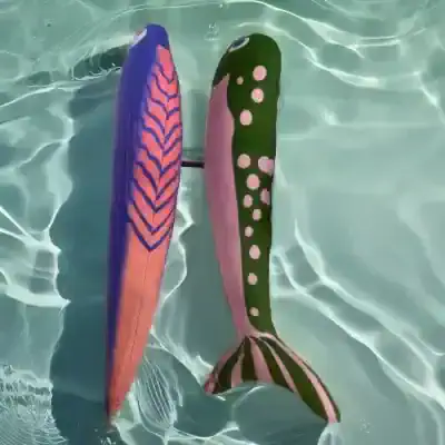 Vibrant pair of colorful sock fins resembling fish fins floating in clear pool water, perfect for aquatic activities and swim training, showcasing fun and functional pool accessories.