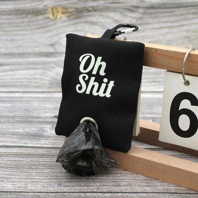 Oh Shit humorous keychain with black fabric, metal ring, and attached black plastic bag, perfect as a quirky accessory for bags or keys. Unique and funny gift idea for friends with a sense of humor.