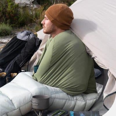 Comfortable outdoor camping setup with a man resting beside his tent, showcasing high-quality outdoor gear and accessories from Monalisa Store.