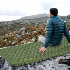 Lightweight camping sleeping pad on rocky mountain with hiker enjoying outdoor adventure.
