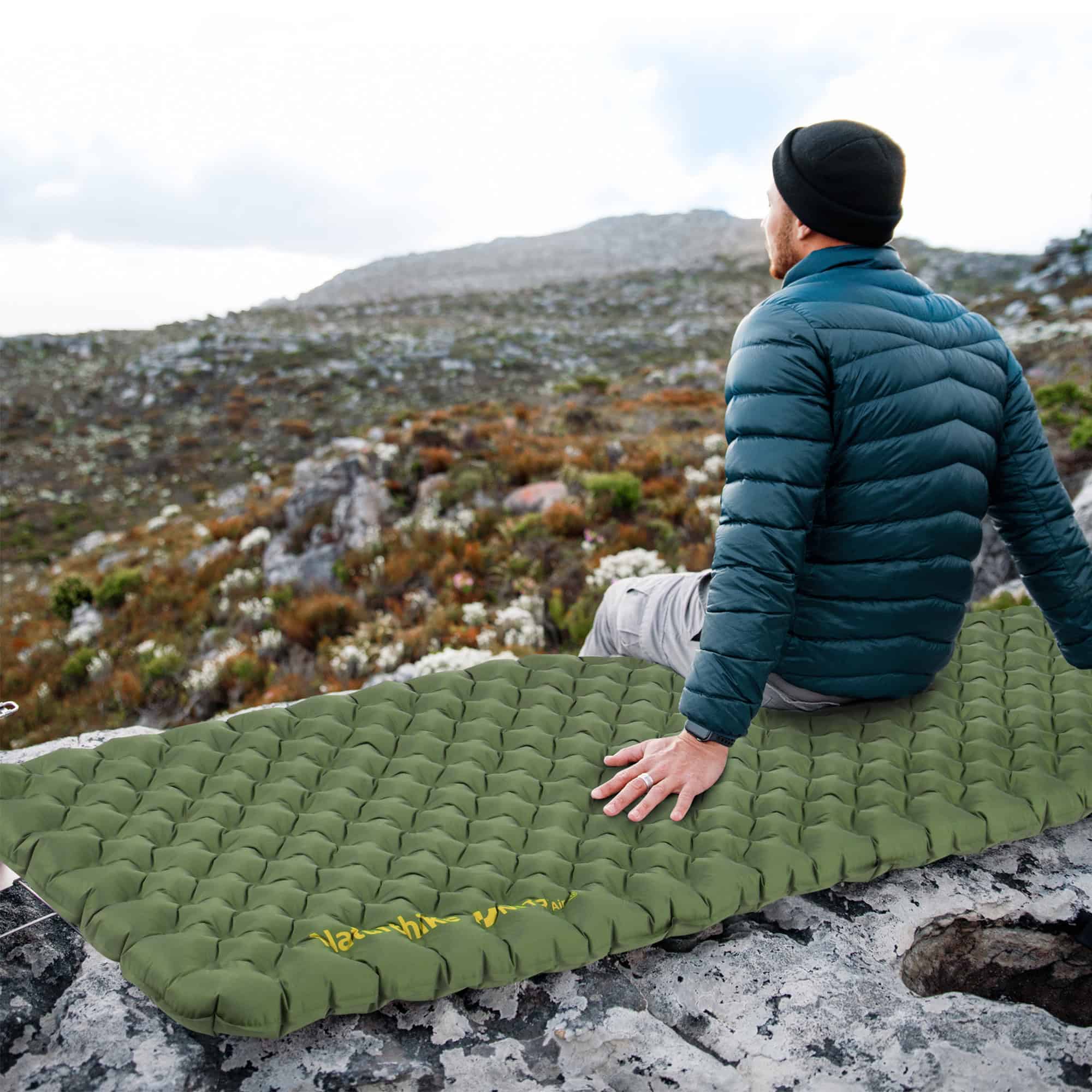 Lightweight camping sleeping pad on rocky mountain with hiker enjoying outdoor adventure.