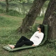 Relaxing woman lying on a green garden lounge near the lake, enjoying nature and outdoor relaxation.