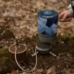 Portable camping stove with fuel canister and cookware; outdoor cooking gear ideal for camping trips and hiking adventures.