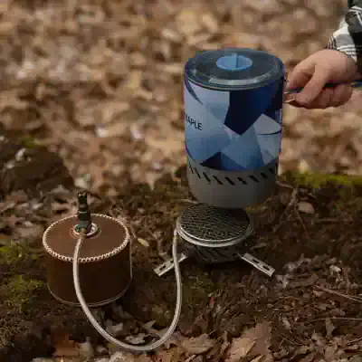 Portable camping stove with fuel canister and cookware; outdoor cooking gear ideal for camping trips and hiking adventures.