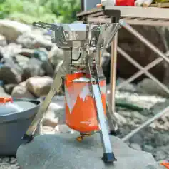 Compact portable camping stove with aluminum construction, perfect for outdoor cooking during camping and hiking adventures. Stainless steel windscreen surrounds the burner for added efficiency.