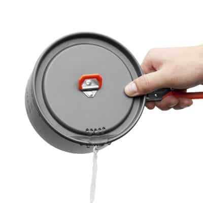 Stainless steel pressure cooker lid with steam vent, held by hand, isolated on white background.