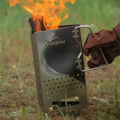 Metal camping stove with burning wood for outdoor cooking, portable lightweight camping gear for hiking and backpacking, durable stainless steel camping cooking stove for outdoor adventures.