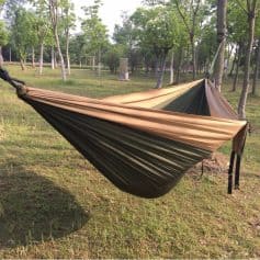 Lightweight camping hammock with adjustable straps in an outdoor wooded setting, perfect for relaxation and outdoor activities.