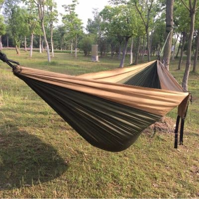 Lightweight camping hammock with adjustable straps in an outdoor wooded setting, perfect for relaxation and outdoor activities.