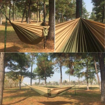 Light brown camping hammock suspended between trees in a wooded outdoor setting for relaxation and outdoor activities, featuring durable material and easy setup.