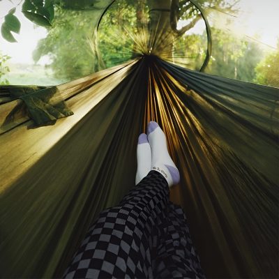 Relaxing outdoor hammock view surrounded by lush greenery with sunlight filtering through the trees.