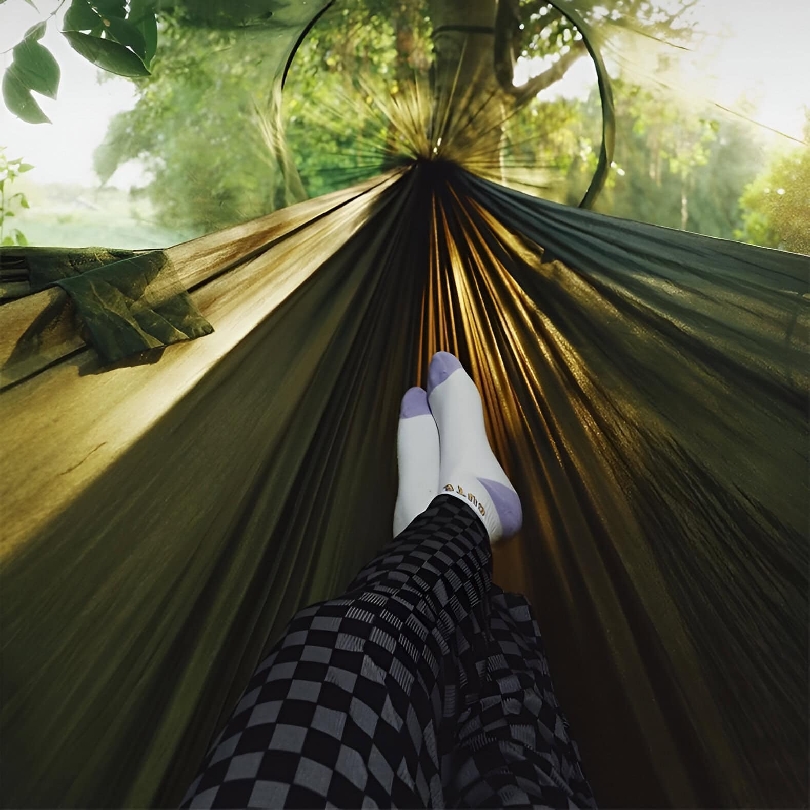 Relaxing outdoor hammock view surrounded by lush greenery with sunlight filtering through the trees.