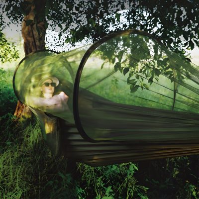 A woman relaxing in a portable outdoor sun tent with UV protection, wearing sunglasses and a sunhat, surrounded by lush greenery. Perfect for outdoor activities like camping, hiking, or backyard relaxation.