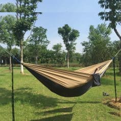 Hammock outdoor relaxing setup between trees in a lush green park, perfect for leisure and recreation, with clear blue sky and natural surroundings.