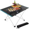 Portable electric grill with food grilling setup on a foldable black table, ideal for outdoor picnic and camping, featuring easy-to-clean surface and adjustable temperature control.
