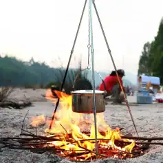 Boiling pot hanging over open campfire outdoor cooking camping gear camping equipment outdoor campfire cooking setup.