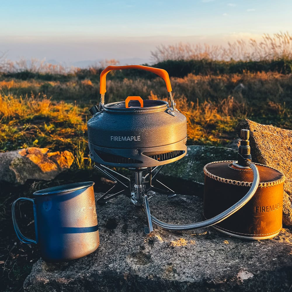 Compact portable camping stove with an orange handle and fuel canister, ideal for outdoor cooking and thermos for beverages. Perfect gear for camping, hiking, and outdoor adventures.
