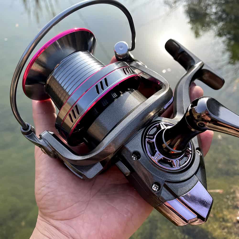 High-quality fishing reel in hand near water, showcasing advanced fishing gear options. Perfect for anglers seeking durable, premium fishing equipment from Monalisa Store.