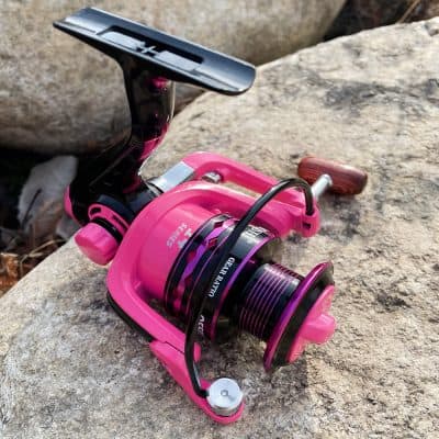 Pink fishing reel with wooden handle on rough stone surface, suitable for advanced angling, part of Monalisa Store aquatic gear collection, optimized for fishing equipment SEO.