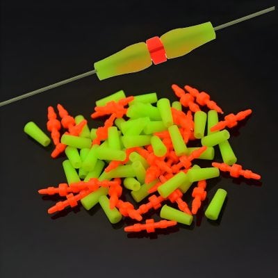 Faintly illuminated electronic components, including orange connectors and green insulating sleeves, arranged on a black background for optoelectronic applications.