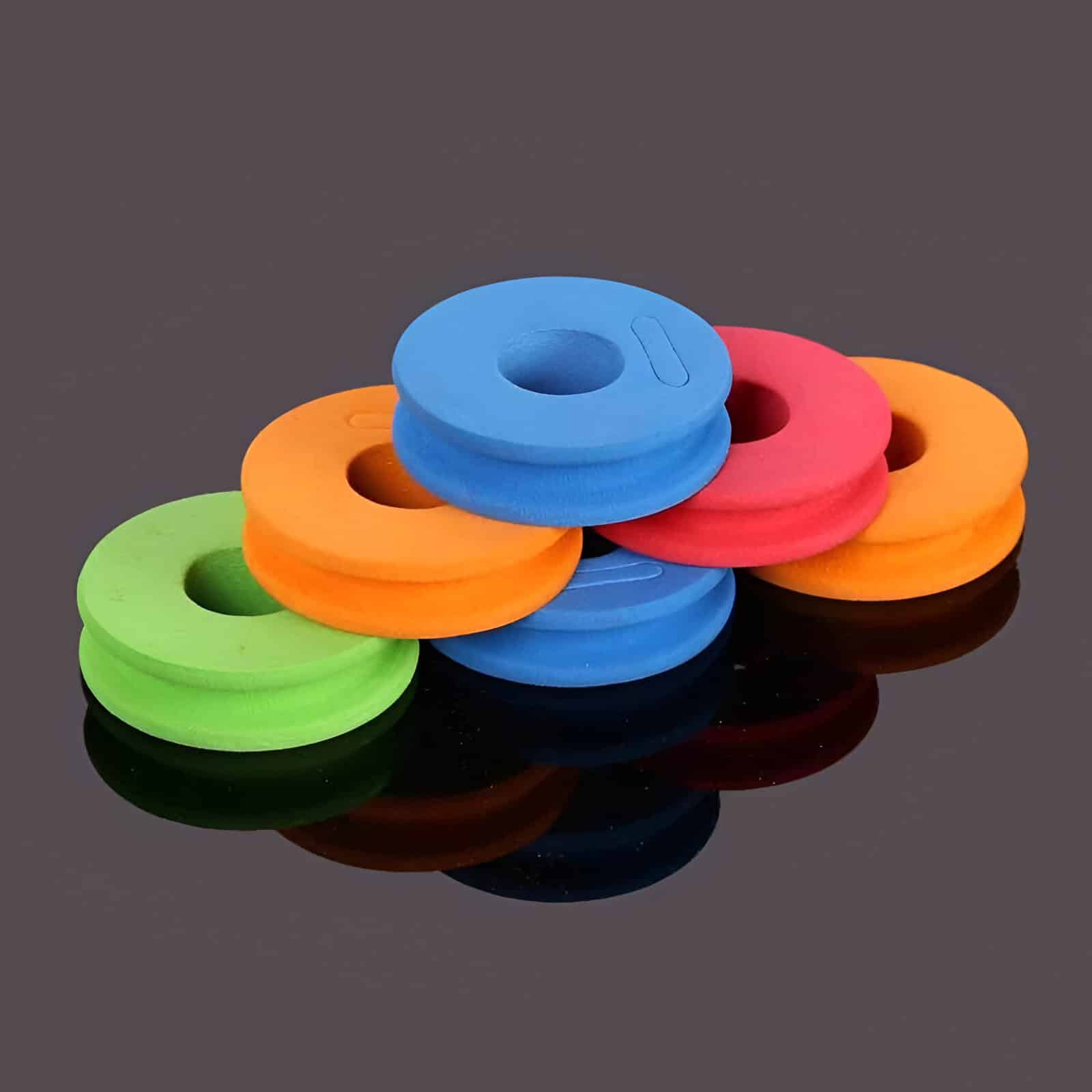 Colorful foam weight plates stacked on a reflective black surface, ideal for fitness and strength training. Vibrant gym accessories perfect for home or gym workouts, enhancing muscle building routines.