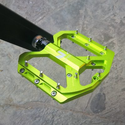 Bright green bicycle pedal with metal studs, lightweight aluminum construction, suitable for mountain and road bikes, durable and high-performance cycling accessory.